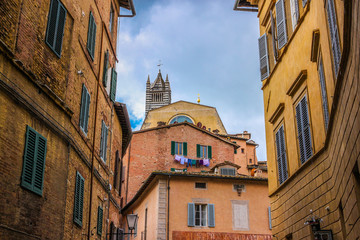 Fototapeta na wymiar Street of medieval Siena with view on historical center and Duomo cathedral. Tuscany, Italy.