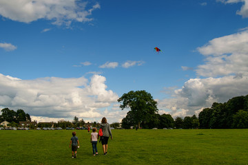 Obraz premium Young woman with children and a kite in blue sky.