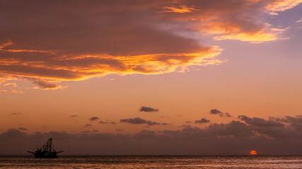 Beautiful sunset above bay with a fishing boat on the horizon