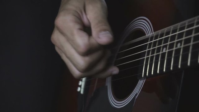 Man playing guitar on black background. Six strings. Playing with fingers