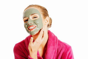 Beautiful woman in pink bathrobe and havinf facial mask.