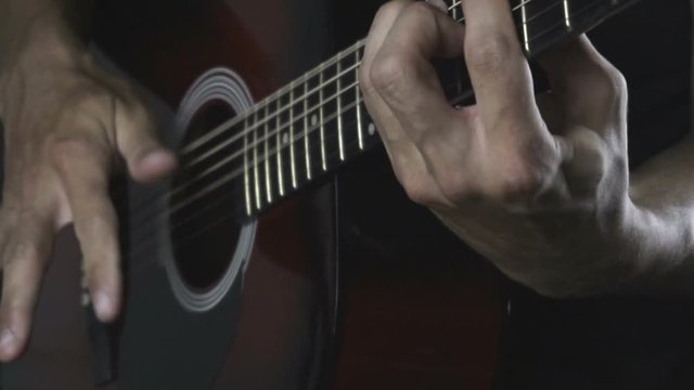 Man playing guitar on black background. Six strings. Playing with fingers