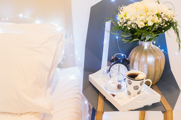Breakfast in bed - bedside tray with cup of coffee and marshmallows, cozy hygge home style