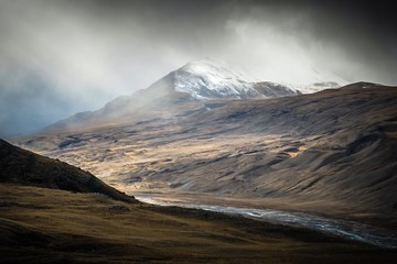 River valley among misty snow- capped mountains 