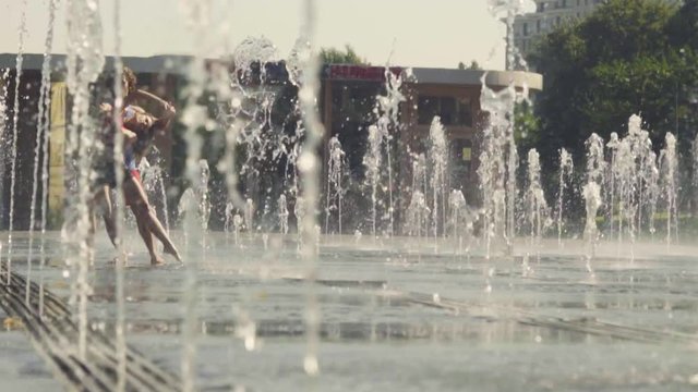 Young happy couple dancing in the fountain