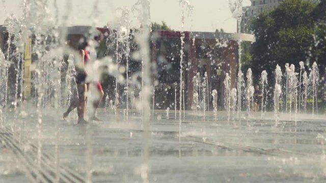 Young happy couple dancing in the fountain