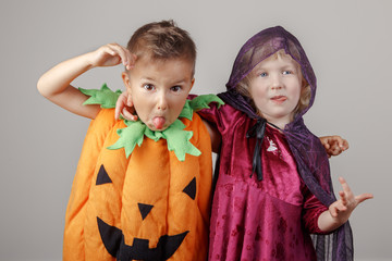 Group portrait of two white Caucasian adorable children dressed for Halloween. Funny kids playing having fun posing in studio for autumn fall seasonal holiday.