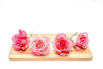 Pink roses lie on wooden board isolated
