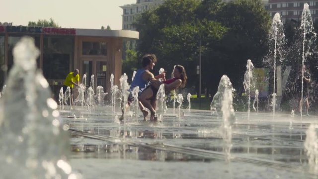 Young happy couple dancing in the fountain