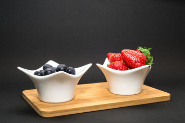 Fruits like blueberry and strawberry on bowl dark background