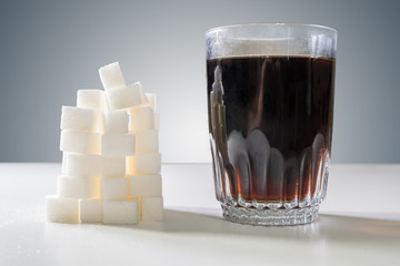 Glass of cola drink and heap of sugar cubes. Unhealthy eating concept.