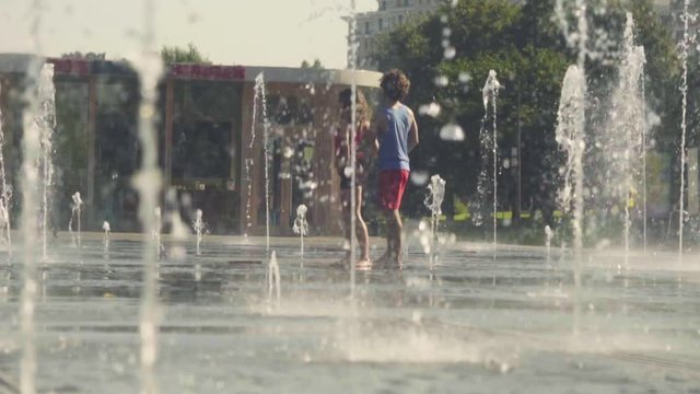 Young happy couple dancing in the fountain