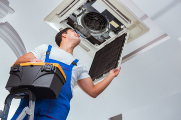 Worker repairing ceiling air conditioning unit