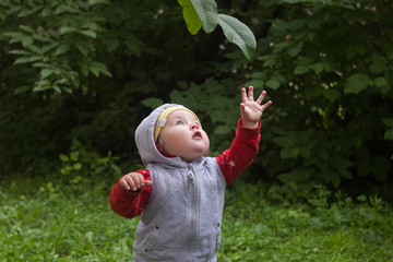 spring or summer time in the park. Little blond caucasian girl playing in the green grass garden