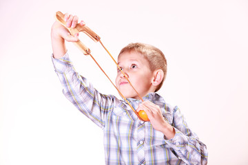 Young boy use sling shot shoot mandarine.