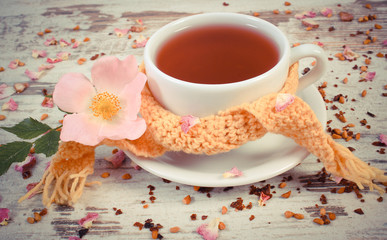 Vintage photo, Hot tea with wild rose flower in cup wrapped scarf