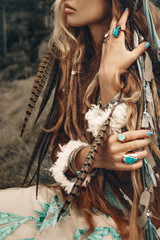 close up of beautiful young boho hands with feathers 
