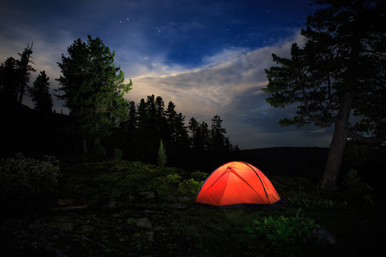 A tent glows under a night sky