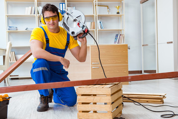 Repairman carpenter cutting sawing a wooden plank with a circula