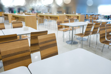 Interior of white table and wooden table on food court in shopping mall.