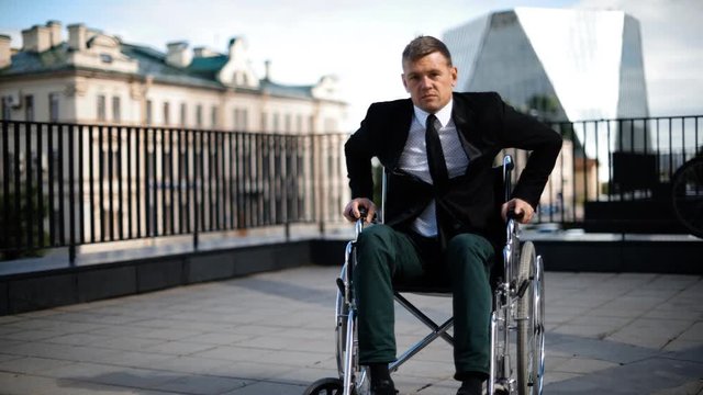 Handicapped businessman trying to get up from wheelchair outdoor. He strained, angry and disappointed of his powerless. Nobody helps him.