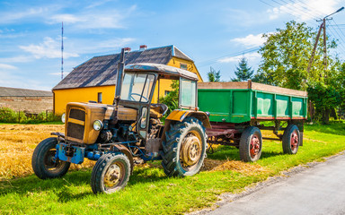 Old red rusty farm tractor at the edge of a field
