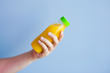 Close-up of female hand holding a bottle with juice