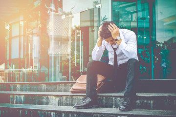 Asian businessman Wearing white shirt sitting stress unemployed on staircase with work  sunset background.