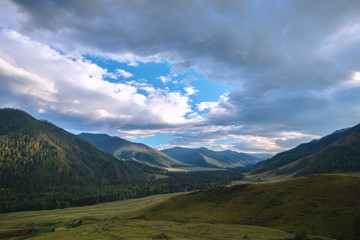 Fototapeta premium fluffy rainy clouds over green hills at sunny day 
