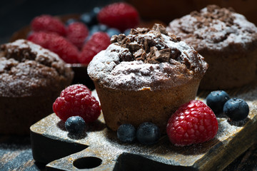 chocolate muffins and fresh berries on dark wooden board