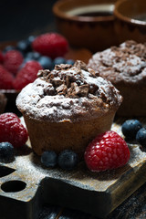 chocolate muffins and fresh berries on dark wooden board, vertical