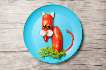 Funny cat made of pepper on plate and wooden background