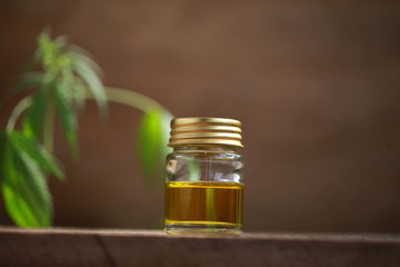 A cannabis leaf and a bottle of hemp oil on a wooden table