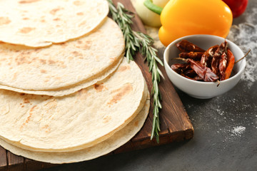Board with delicious tortillas on kitchen table