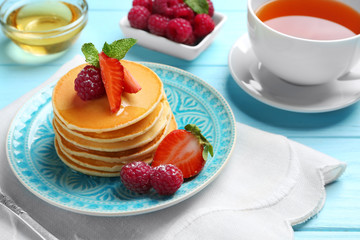 Plate with delicious pancakes on table