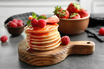 Delicious pancakes with raspberry and strawberry on wooden board