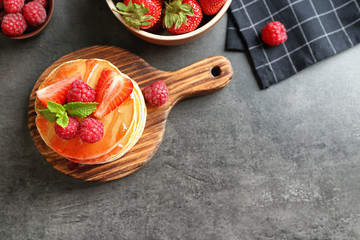 Delicious pancakes with raspberry and strawberry on wooden board