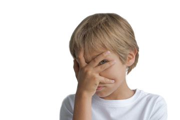 Boy covering his face with hand and looking at camera through fingers isolated on white background