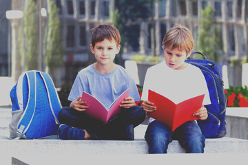 Children reading books outdoors.