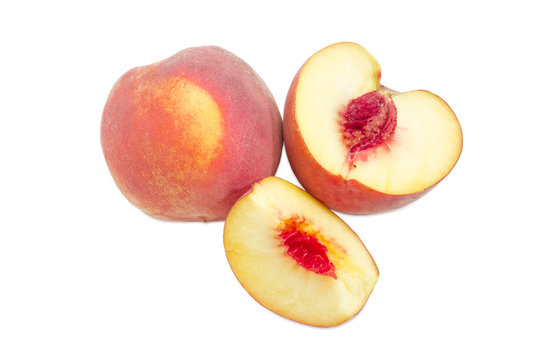 Whole and sliced peach on a white background