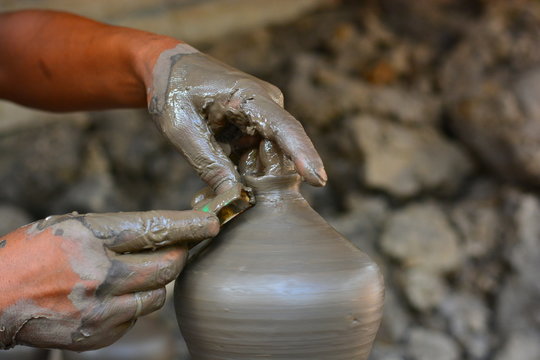 close up on hands making pots on pottery wheel