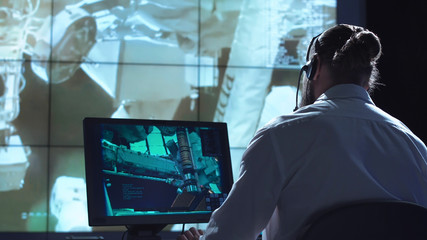 Movement shot back view of man working on space mission in control center. Elements of this image furnished by NASA.