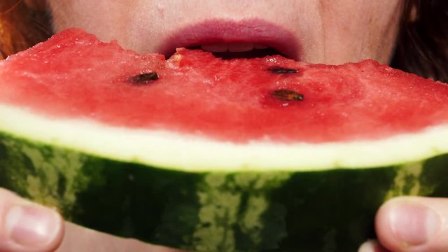 Closeup of mature woman eating fresh red watermelon fruit. Healthy food organic nutrition. 4K ProRes HQ codec
