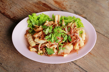 Fried squid in plate on wood table.
