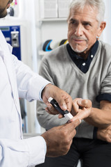 Doctor Checking Of Senior Patient's Sugar Level With Glucometer