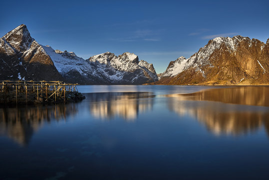Scenic fjord on Lofoten islands, with typical red fishing hut and towering mountain peaks, Sakrisoy, Norway