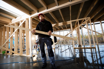 Fototapeta premium Portrait Of Carpenter Carrying Wood At Site