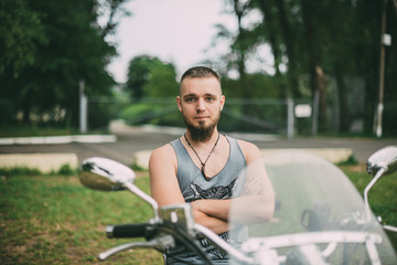 Красивый молодой мужчина с бородой сидит на мотоцикле на фоне природы