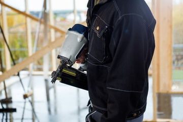 Midsection Of Carpenter Holding Drill Machine At Site