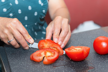 woman cutting tomato with the knife, on a  plate